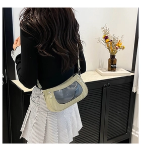 Detail of light green crossbody bag featuring PVC clear window and star metal rivets