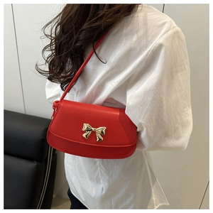 Détail du sac bandoulière rouge avec fermoir élégant en forme de nœud doré