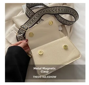 Detailed close-up of metal magnetic snaps on a woven cream-colored crossbody bag