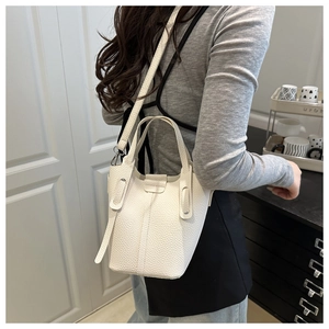 Detailed view of white lychee leather bucket bag with dual handles and crossbody strap