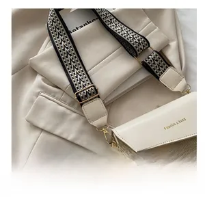 Detail of beige leather crossbody bag with geometric wide strap and gold fashion logo