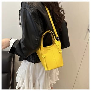 Yellow pebbled leather bucket bag with top handle and crossbody strap styled on model