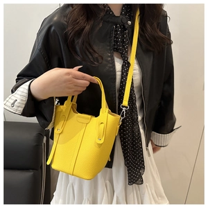 Close-up of bright yellow litchi grain leather bucket bag with silver hardware on model