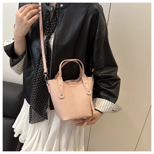 Pink lychee grain leather bucket bag detail with adjustable shoulder strap and handle