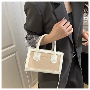 Détail du sac à main en toile bicolore avec garniture en cuir blanc et logo doré