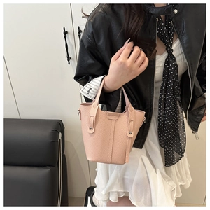 Pink pebbled leather bucket bag styled on model showcasing compact size and shoulder strap