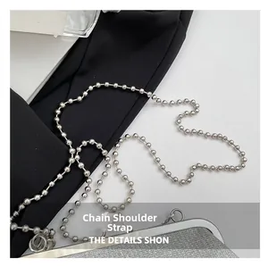Détail macro de la bandoulière chaîne à billes argentées sur sac pailleté