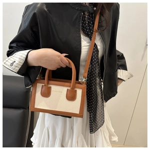 Détail d'un sac cabas en toile bicolore avec poignées en cuir marron et logo Aisly 1986