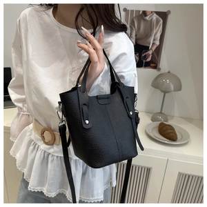 Detail of black pebbled leather bucket bag with silver hardware on a lifestyle background
