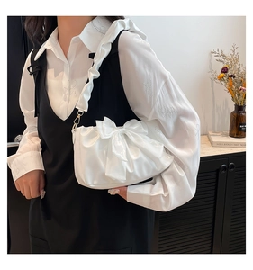 Gros plan du sac en satin blanc avec nœud décoratif et détails de bandoulière plissée