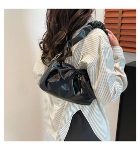 Détail du sac nuage plissé noir avec un nœud en soie assorti et une large bandoulière