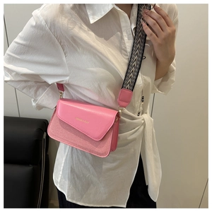 Detail of pink crossbody bag featuring woven texture and geometric wide shoulder strap