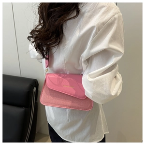 Detailed shot of a pink crossbody bag featuring textured fabric and leather patchwork design