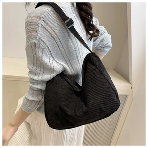 Dettaglio borsa tote in velluto a coste nero con tracolla indossata da modella