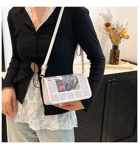 Detail view of white newspaper print crossbody bag with gold hardware and slim strap on model