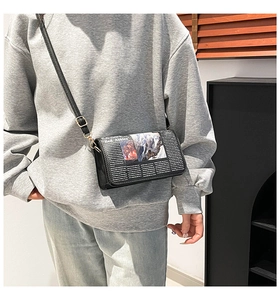 Close-up of the vintage newspaper print design and magnetic flap on a black crossbody bag