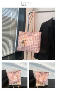 Dettaglio della borsa tote a scacchi rosa con manici e ciondolo a forma di orsetto