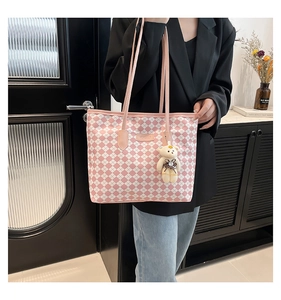 Dettaglio della borsa tote a scacchi rosa con ciondolo a forma di orsetto e logo