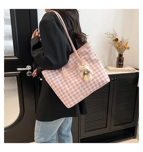 Modella che indossa una grande borsa tote a scacchi rosa e bianchi con ciondolo a forma di orso