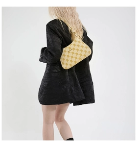 Dettaglio borsa baguette color crema con stampa monogramma su blazer nero strutturato
