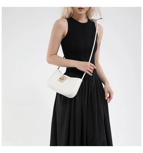 Detail of white leather shoulder bag with structured frame and elegant gold metal lock buckle