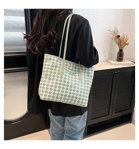 Vista dettagliata della grande borsa tote a scacchi verde e bianca indossata da una modella