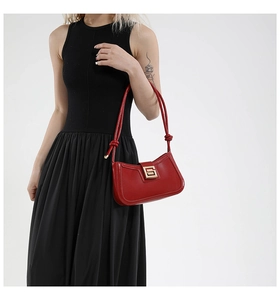 Macro shot of red leather shoulder bag featuring a gold square buckle with S-shaped logo