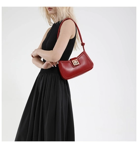 Close-up of a red leather underarm bag with gold buckle on a model in a black dress
