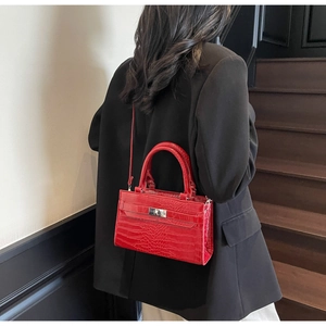Detailed view of red crocodile embossed leather handbag with silver metallic twist lock closure