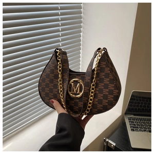 Close-up of crescent-shaped brown bag featuring letter M pattern and gold metal buckle