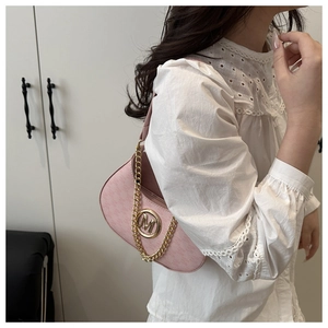 Detail view of pink matte underarm bag with gold M logo and chain strap on shoulder