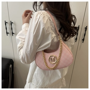 Detailed shot of pink crescent underarm bag with gold M logo and chain on model