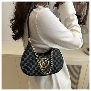 Detail of monogram patterned shoulder bag with gold M-logo buckle and leather strap