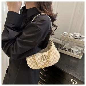 Close-up of cream shoulder bag with brown M jacquard pattern and golden metal logo
