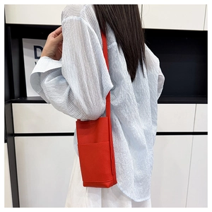 Detailansicht der roten Handytasche aus Leder mit Litschimuster und Schultergurt vorne