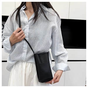 Minimalistische schwarze Umhängetasche aus genarbtem Leder für Damen am Modell gezeigt