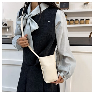 Detail der weißen Eimer-Tasche mit Litschitextur und Frontfach für das Handy