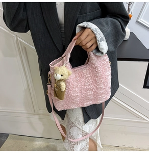 Detailed view of pink pleated bucket bag with a cute bear charm and crossbody strap