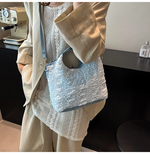 Détail du tissu gaufré bleu clair et de la bandoulière en cuir d'un sac à main chic
