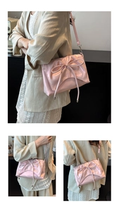 Detail of pink ballet-style shoulder bag with glossy finish and ribbon bow design