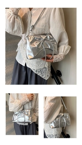 Detailed view of shiny silver crossbody bag featuring a large decorative bow