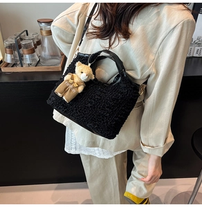 Detail of black textured puffy hobo bag featuring a cute bear charm and leather strap