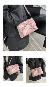 Detail of pink bow shoulder bag with pearl tassel charm and adjustable metal buckle