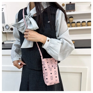 Pink crossbody phone bag with cute bear print and letter detail worn by a model