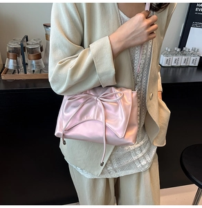 Sac à bandoulière en satin rose avec grand nœud et finition soyeuse sur modèle