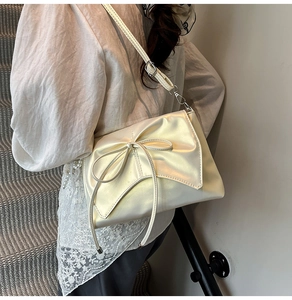 Sac fourre-tout beige avec nœud, sangle en perles et dentelle porté par un mannequin