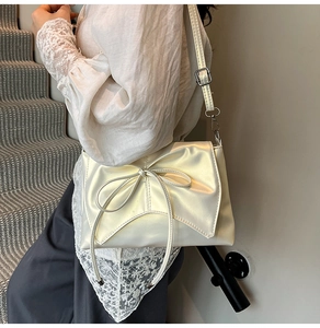 Détail d'un sac à bandoulière en cuir verni blanc crème orné d'un grand nœud décoratif