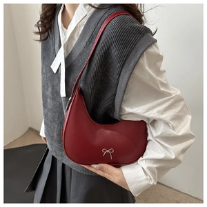 Detail of red crescent hobo bag with a silver metallic bow and stylish leather shoulder strap