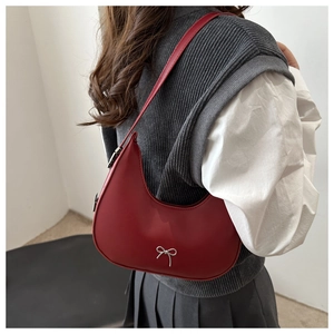 Model wearing a red leather half-moon shoulder bag with a silver bow ornament