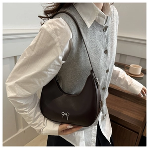 Detail of dark brown crescent underarm bag with silver bow buckle on model
